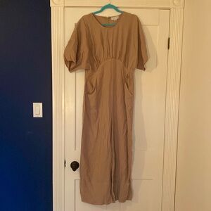 Wide leg, short-sleeved beige jumpsuit with pockets and unique tailored waist.